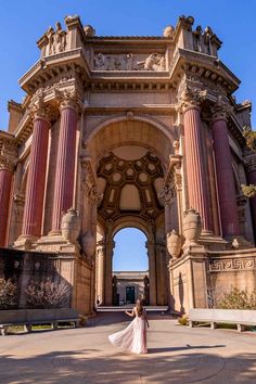 a woman standing in front of an old building with columns and arches on the sides