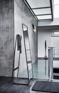 a large mirror sitting on top of a floor next to a metal rack filled with clothes