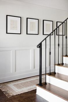 a staircase with pictures on the wall next to it and rug in front of it