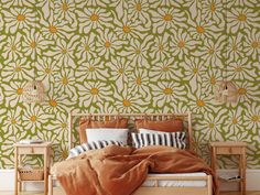 a bed sitting in front of a green wallpaper with orange flowers and leaves on it