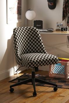 a black and white checkered office chair sitting on top of a wooden floor next to a desk