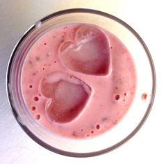 a glass filled with liquid and two hearts in it's center, sitting on a table