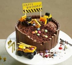 a birthday cake with construction vehicles and dirt on the top is sitting on a white plate