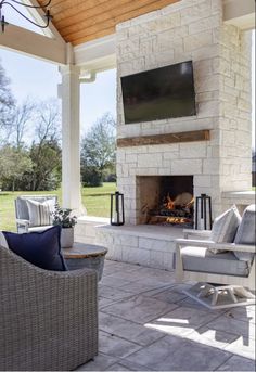 an outdoor living area with furniture and a flat screen tv mounted on the wall above a fireplace