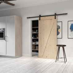 an open sliding door in a kitchen with white cabinets and wood floors, along with a bar stool