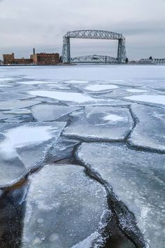 ice floes on the water with a bridge in the background