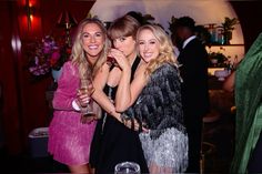 three beautiful young women standing next to each other at a formal event with drinks in their hands