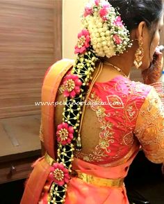 a woman in an orange and pink sari with flowers on her head is talking on the phone