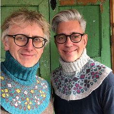 two people standing next to each other in front of a green door