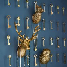 there are many keys on the wall and two deer heads hanging from it's sides