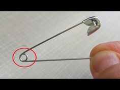 a person is holding onto a metal pin with a red circle on the end of it