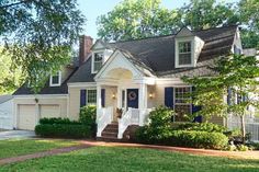 a white house with blue shutters in the front yard