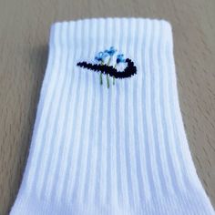 a pair of white socks with blue flowers on them sitting on top of a table