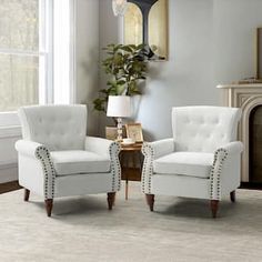 a living room with two white chairs and a fireplace