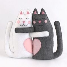 two felt cats hugging each other on a white background