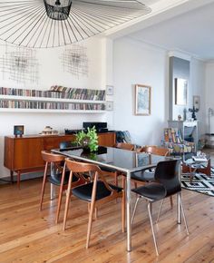 a dining room table with chairs and bookshelves on the wall in front of it