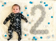 a baby laying on top of a blanket next to the number twenty two written in snowflakes