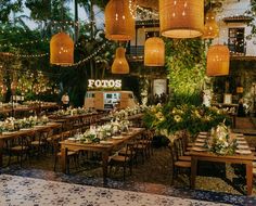 the tables are set up for an event with hanging lights and greenery in the background