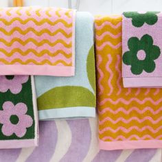 towels hanging up on a rack in a bathroom with flowers and chevron stripes around them