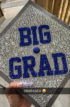 someone holding up a graduation cap with the words big grad in blue on it