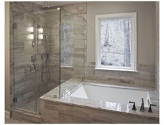 a bathroom with a large tub and walk in shower next to a window on the wall