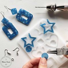 someone is making some earrings out of ice cubes and star cutouts with scissors