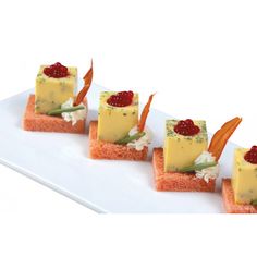 four small pieces of food on a white plate with garnish and toppings