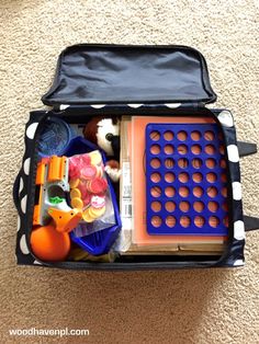 an open suitcase with toys in it on the floor next to a carpeted area