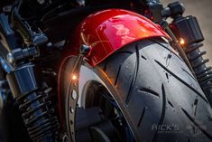 the front tire of a red motorcycle with its brake lights on and it's light on