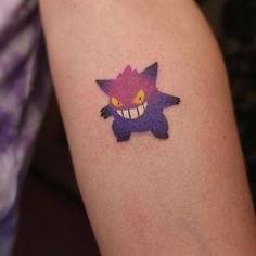 a person with a tattoo on their arm that has a cat face and yellow eyes