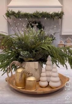 a potted plant sitting on top of a wooden platter filled with christmas decorations