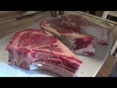 raw meat sitting on top of a wooden cutting board next to tomatoes and parsley