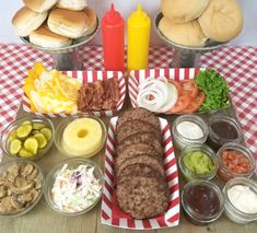 a table topped with lots of food and buns on top of a red and white checkered table cloth