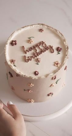 a woman is cutting into a cake with the word happy on it and pink flowers