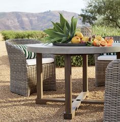 a table with some fruit on top of it next to wicker chairs and trees