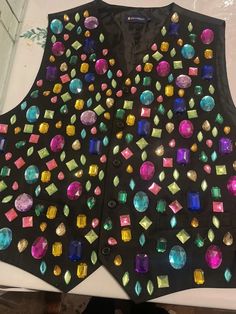 a black vest with lots of different colored stones on it