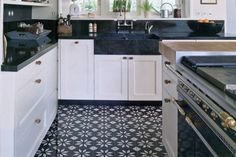 a kitchen with white cabinets and black counter tops is seen in this image from the doorway