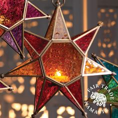 a multicolored glass star hanging from a chandelier with a lit candle in the center