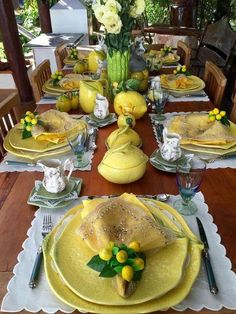 the table is set with yellow dishes and place settings