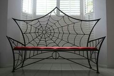 a spider web on the back of a bench in front of two windows with white shutters