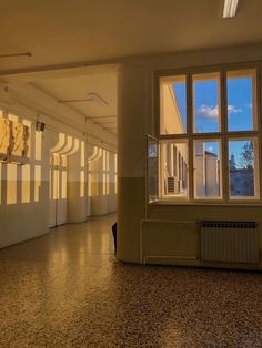 an empty room with several windows and paintings on the wall