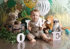 a baby sitting on the floor in front of some stuffed animals and letters that spell out love