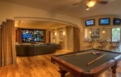 a living room with a pool table and televisions