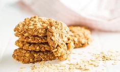 three oatmeal cookies stacked on top of each other next to a pile of oats