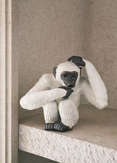 a small statue of a monkey sitting on top of a ledge next to a wall