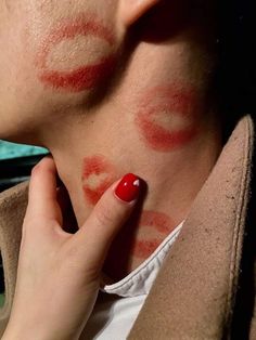 a woman with red nail polish on her face and neck, looking at the camera