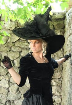 a woman wearing a black dress and hat