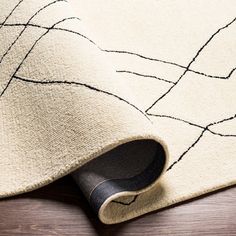 a white rug with black lines on the top and bottom, laying on a wooden floor