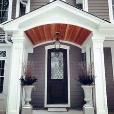 the front door of a house with two planters and a lantern on it's side