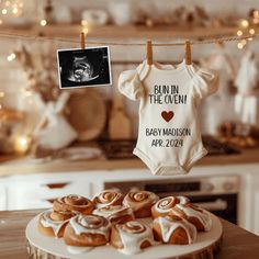 a baby bodysuit hanging on a clothes line with buns and pastries in front of it